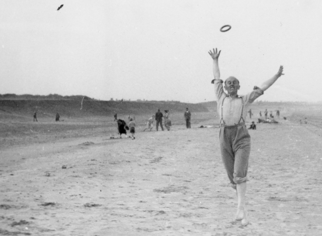 A man jumping for a throwing ring on a sandy beach.